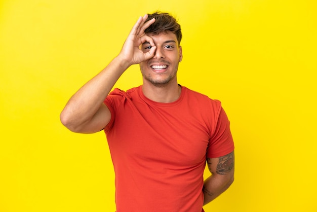 Young caucasian handsome man isolated on yellow background showing ok sign with fingers