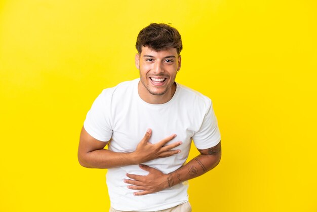 Young caucasian handsome man isolated on yellow background smiling a lot