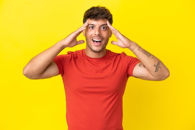 Young caucasian handsome man isolated on yellow background with surprise expression