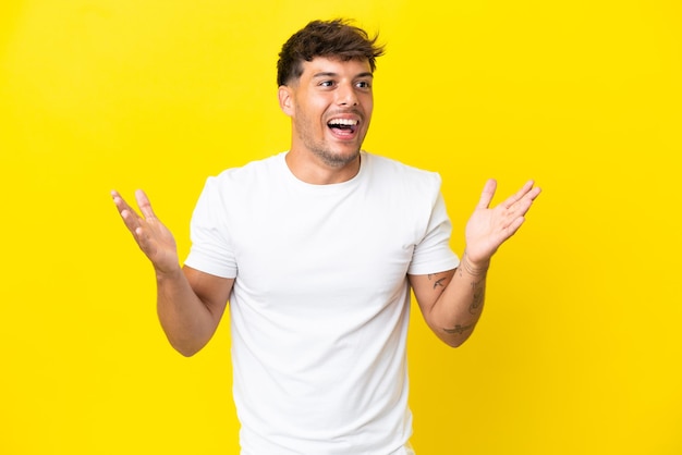 Young caucasian handsome man isolated on yellow background with surprise facial expression