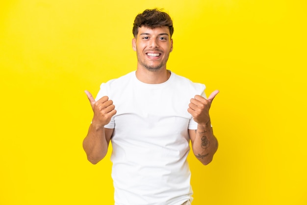 Young caucasian handsome man isolated on yellow background with thumbs up gesture and smiling