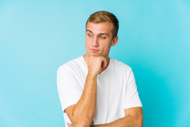 Young caucasian handsome man looking sideways with doubtful and skeptical expression.