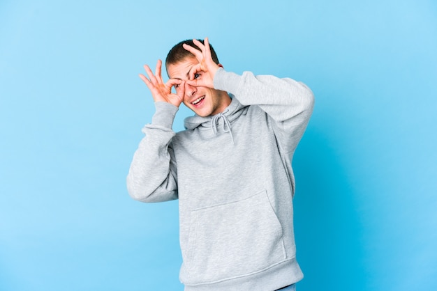 Young caucasian handsome man showing okay sign over eyes