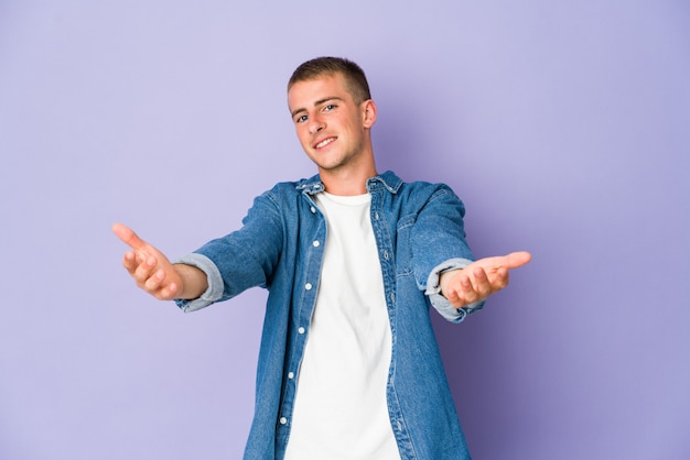 Young caucasian handsome man showing a welcome expression.