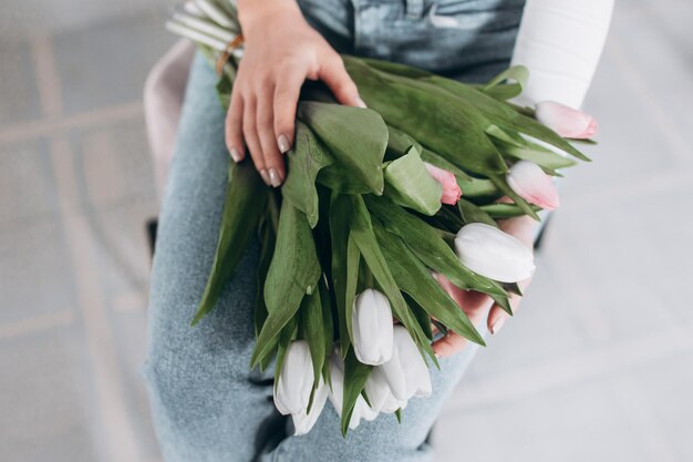 家で新鮮なチューリップの花束の匂いを嗅ぐ若い白人の幸せな女性。