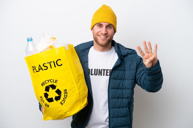 Young caucasian holding a bag full of plastic bottles to recycle isolated on white background happy and counting four with fingers