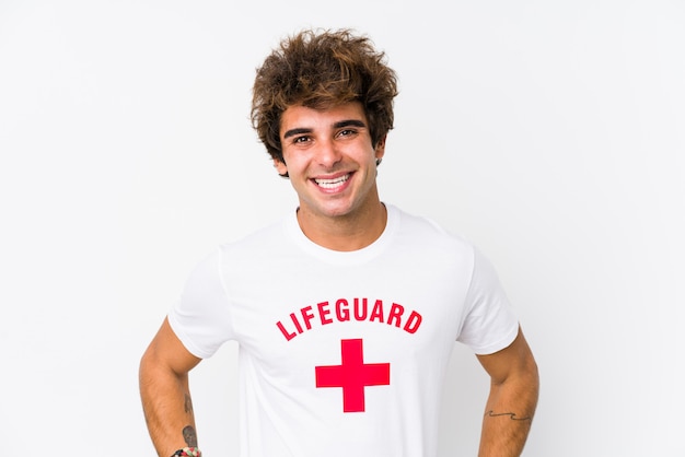 Young caucasian life guard against a white wall isolated confident keeping hands on hips.