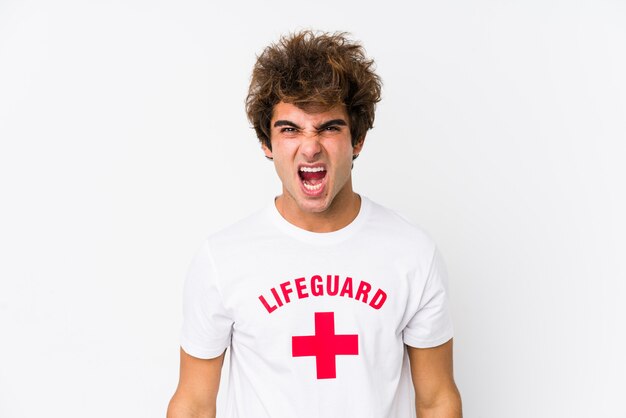 Young caucasian life guard against a white wall isolated screaming very angry and aggressive.