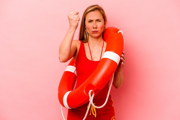 Young caucasian life guard woman isolated on pink background showing fist to camera aggressive facial expression