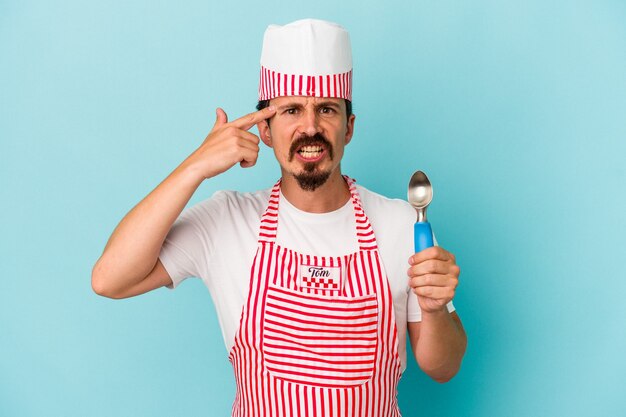 Young caucasian maker holding a scoop isolated on blue background showing a disappointment gesture with forefinger.