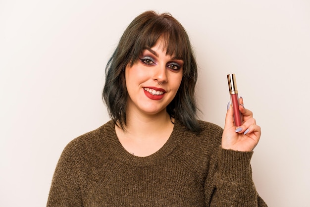 Young caucasian makeup artist woman holding a lipgloss isolated on white background happy smiling and cheerful