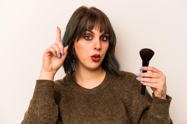 Young caucasian makeup artist woman holding a makeup brush\
isolated on white background having some great idea concept of\
creativity