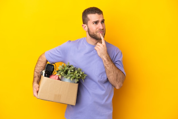 Young caucasian making a move while picking up a box full of things isolated