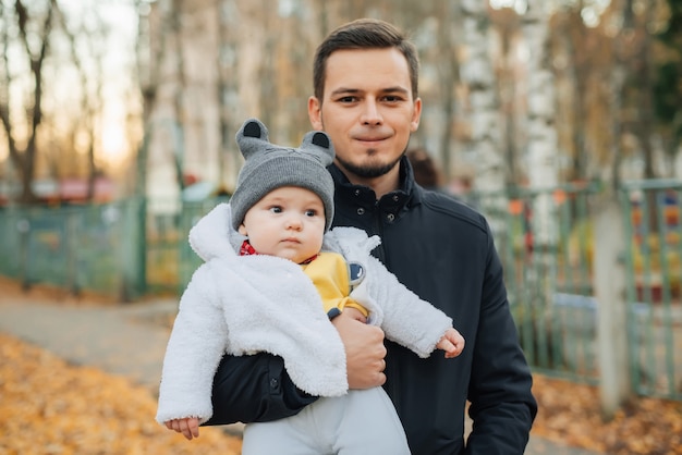 Young Caucasian male dad holds his baby little boy son in his hands