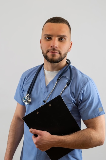 Young caucasian male doctor holding a clipboard isolated