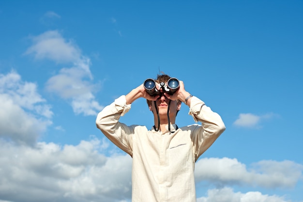 Photo a young caucasian male looking at a view with binoculars under the sky