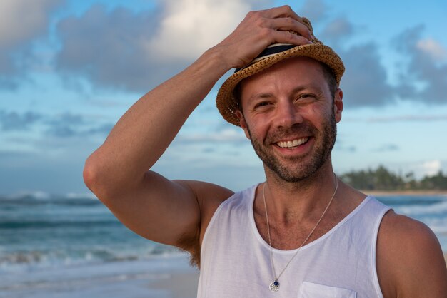 Young caucasian male standing on Sunset Beach in Hawaii wearing a straw hat