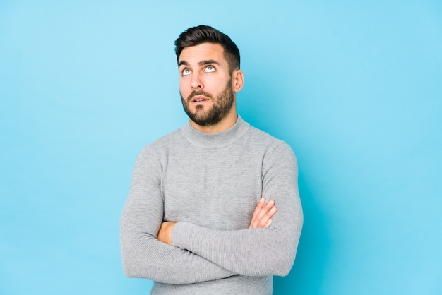 Young caucasian man against a blue wall isolated tired of a repetitive task.