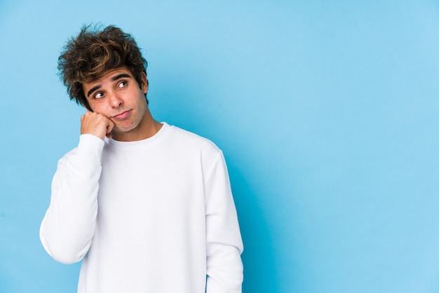 Young caucasian man against a blue wall isolated who feels sad and pensive, looking at copy space.