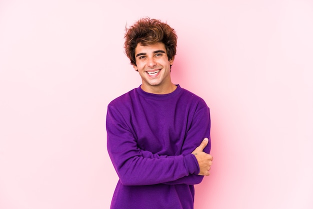 Young caucasian man against a pink background isolated who feels confident, crossing arms with determination.