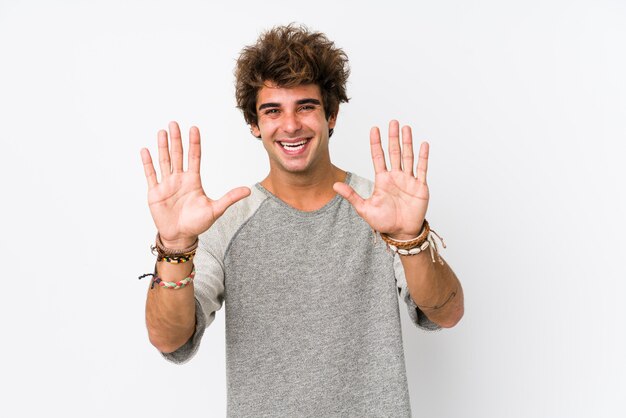 Young caucasian man against a white wall isolated showing number ten with hands.
