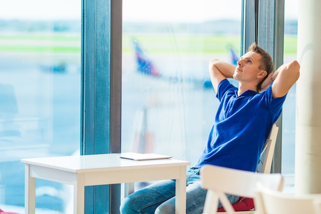 Young caucasian man at airport indoor waiting for boarding