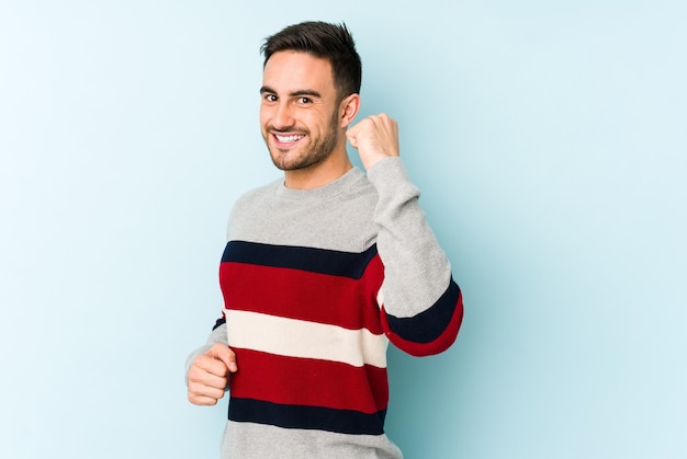 Young caucasian man on blue cheering carefree and excited. Victory concept.