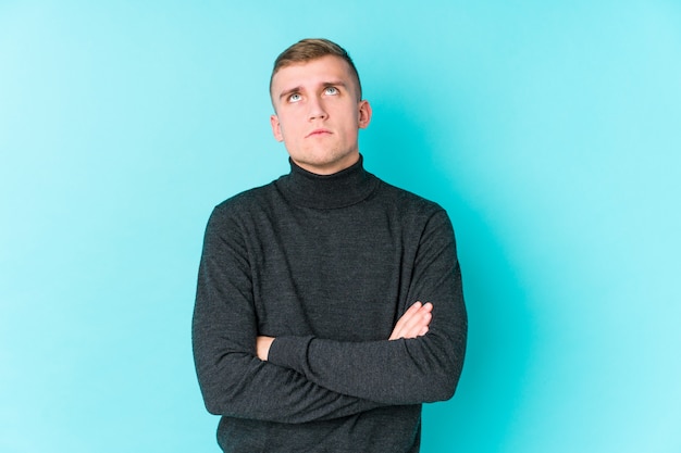 Young caucasian man on a blue wall tired