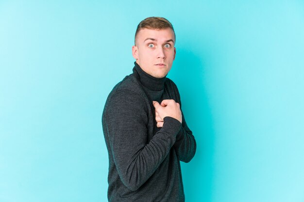 Young caucasian man on a blue wall