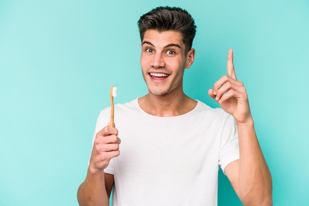 Young caucasian man brushing teeth isolated on white background having an idea, inspiration concept.