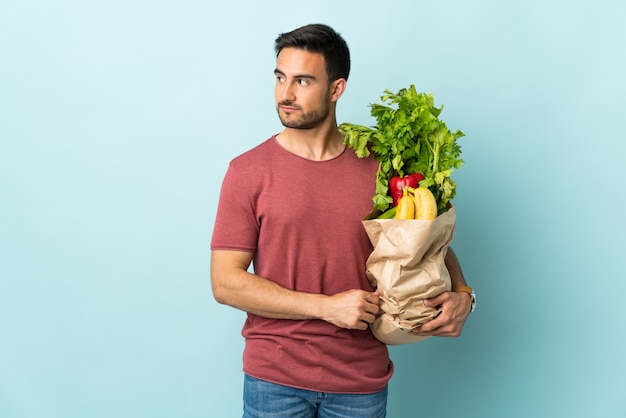 Young caucasian man buying some vegetables isolated