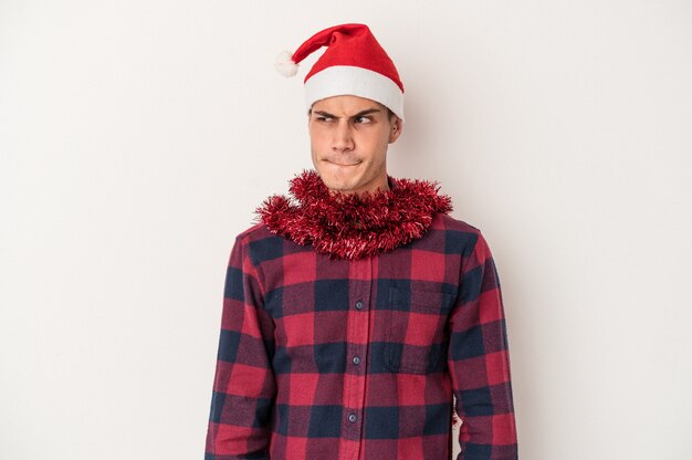 Young caucasian man celebrating Christmas isolated on white background confused, feels doubtful and unsure.