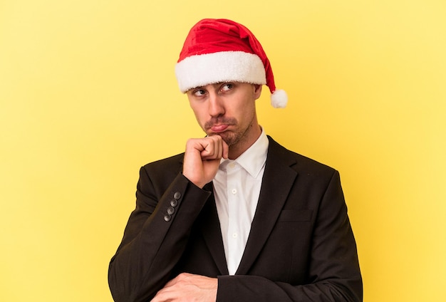 黄色の背景で隔離のクリスマスの帽子をかぶって新年を祝う若い白人男性
