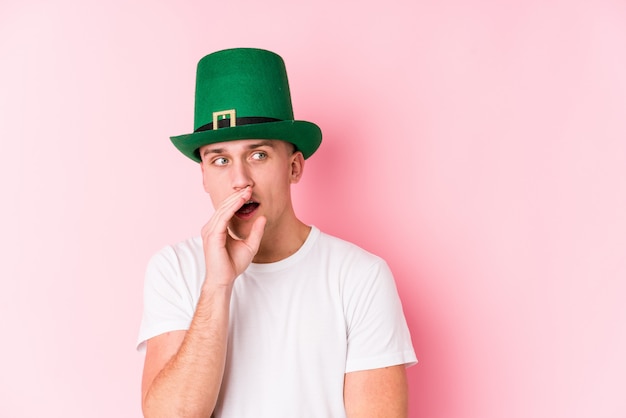 Young caucasian man celebrating saint patricks day is saying a secret hot braking news and looking aside