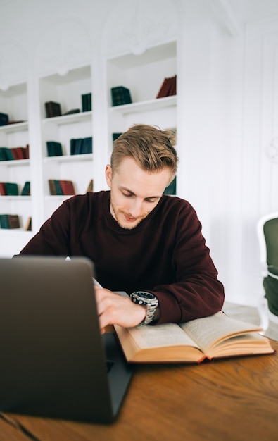 Young caucasian man college student studying with laptop distantly preparing for test exam