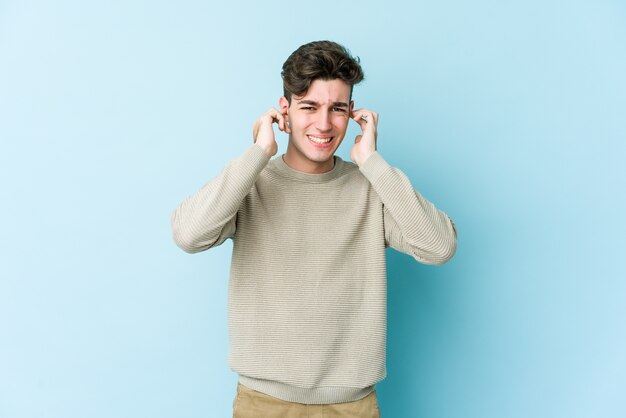 Giovane uomo caucasico che copre le orecchie con le mani.