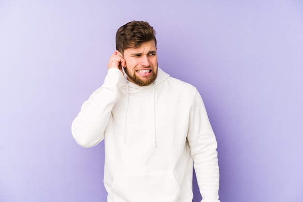 Young caucasian man covering ears with hands.