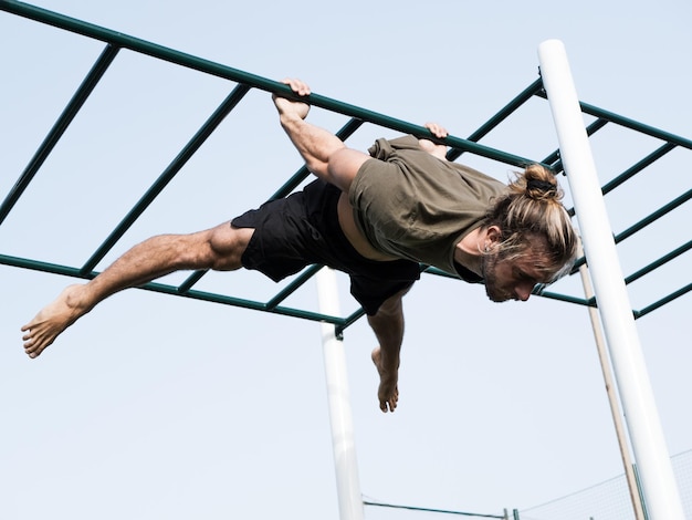 Young caucasian man doing calisthenics exercise hanging on the bars