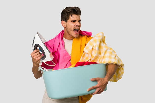 Young caucasian man doing laundry and holding aa iron isolated