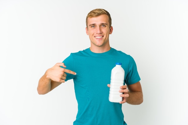 Молодой кавказский мужчина пьет молоко на белом фоне, кусая ногти, нервничает и очень тревожится.