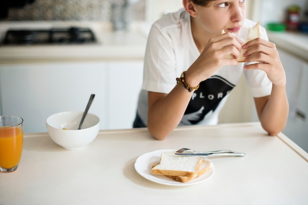 Young caucasian man eating sandwich in kitchen