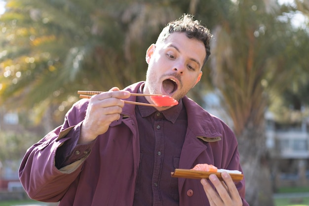 Young caucasian man eating sashimi at outdoors