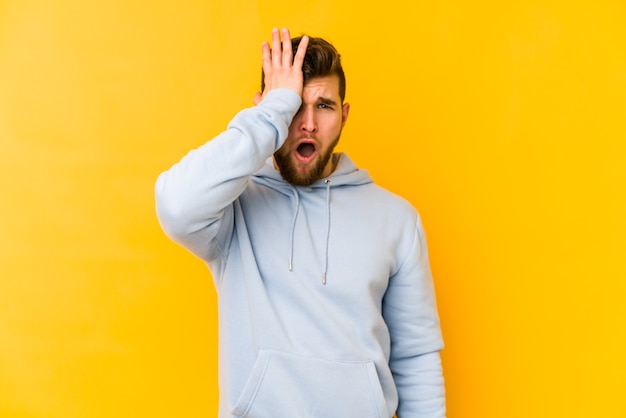 Young caucasian man forgetting something, slapping forehead with palm and closing eyes.