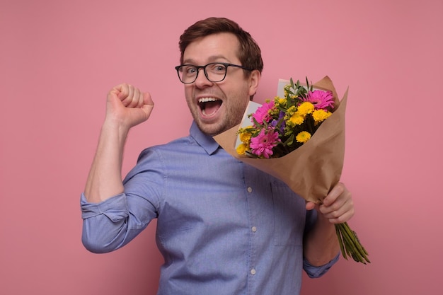 Young caucasian man in glasses having surprised face with flowers for his girlfriend