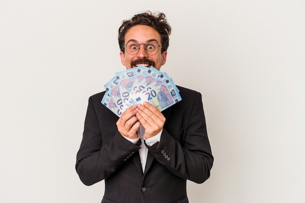 Young caucasian man holding banknotes isolated on pink background