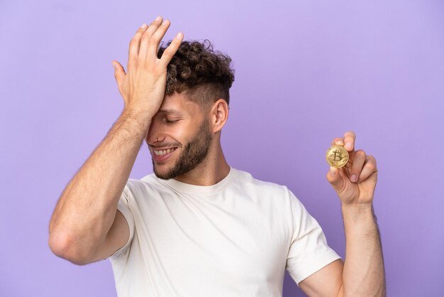 Young caucasian man holding a bitcoin isolated on purple background has realized something and intending the solution