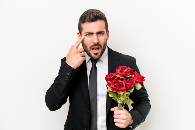 人差し指で失望のジェスチャーを示す白い背景で隔離の花の花束を保持している若い白人男性