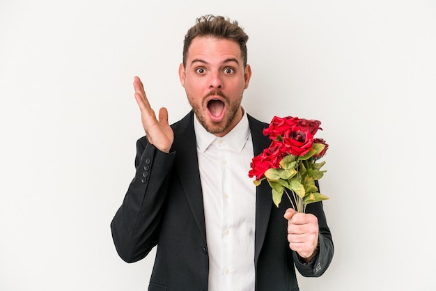 Young caucasian man holding bouquet of flowers isolated on white background surprised and shocked.