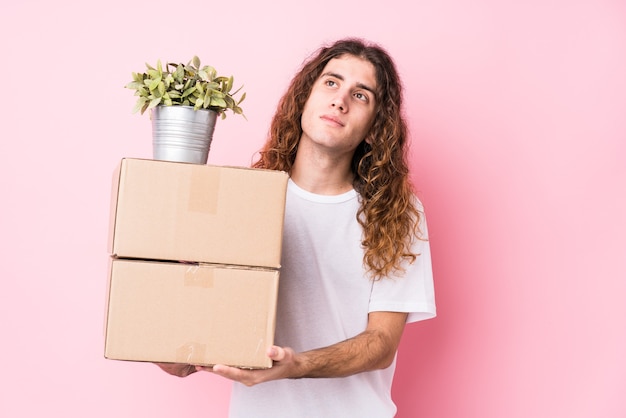 Young caucasian man holding boxes isolated dreaming of achieving goals and purposes