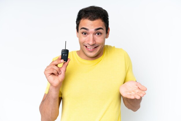 Young caucasian man holding car keys isolated on white background with shocked facial expression